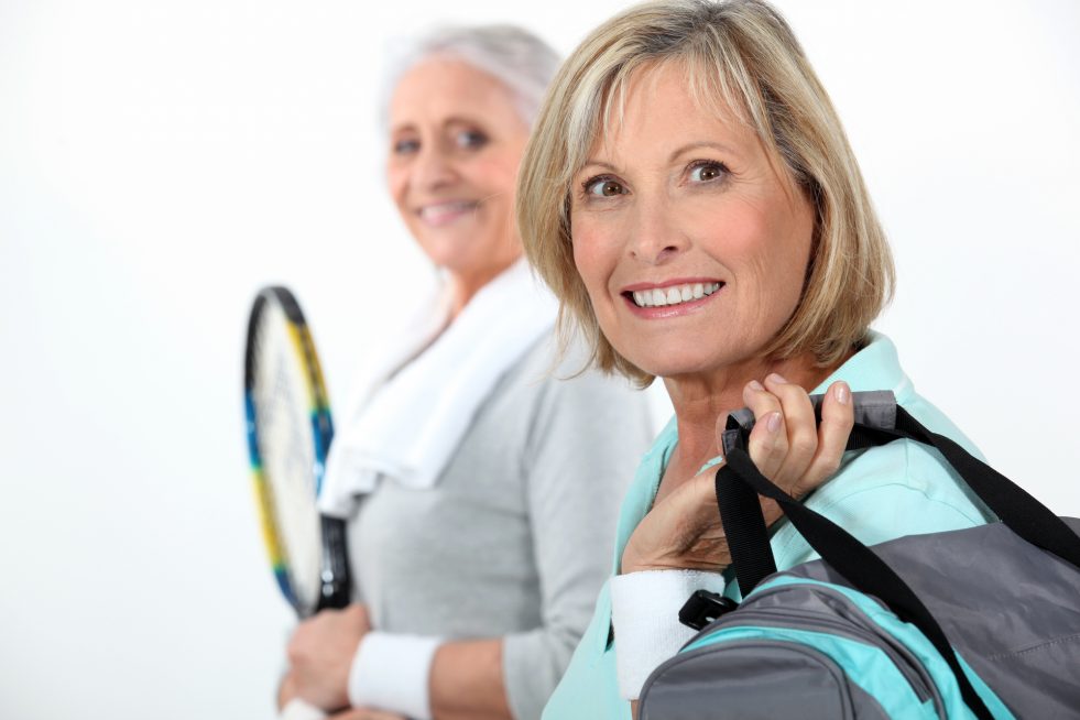 Two mature women playing tennis.