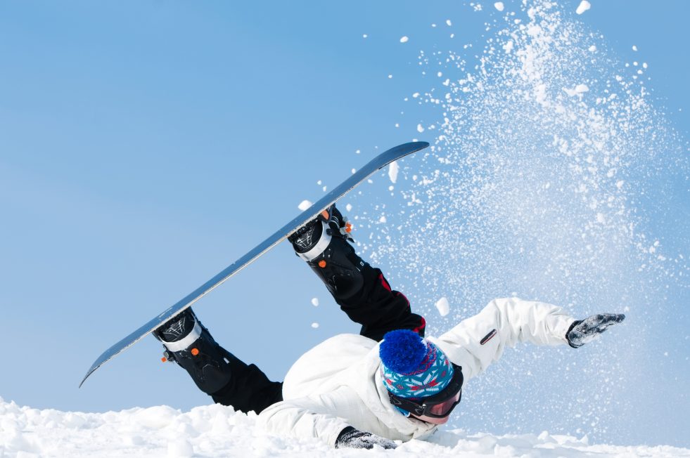 falling young man on snowboard at snowy winter.