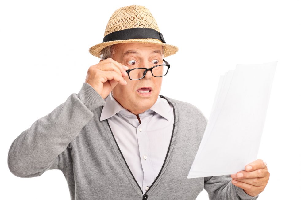 Man looking at piece of paper with a look of surprise on his face.