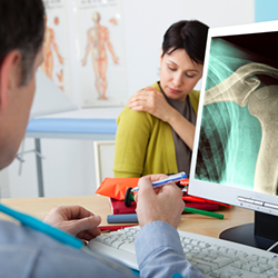 Woman describing shoulder pain to her doctor.