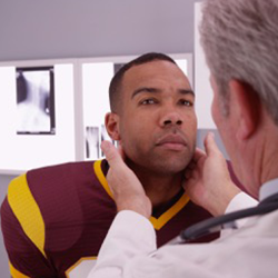 Photo of a doctor examining a man's neck.