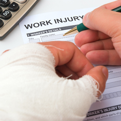 Man with injured hand filling out worker's comp paperwork.