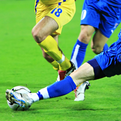 closeup of legs kicking a soccer ball.