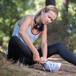 athlete rubbing her ankle in pain.