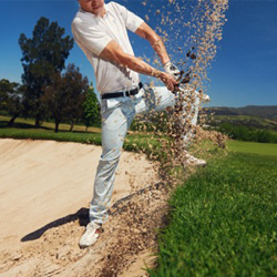 golfer hitting ball out of a sand trap.