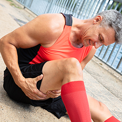 man holding his hamstring wincing in pain.