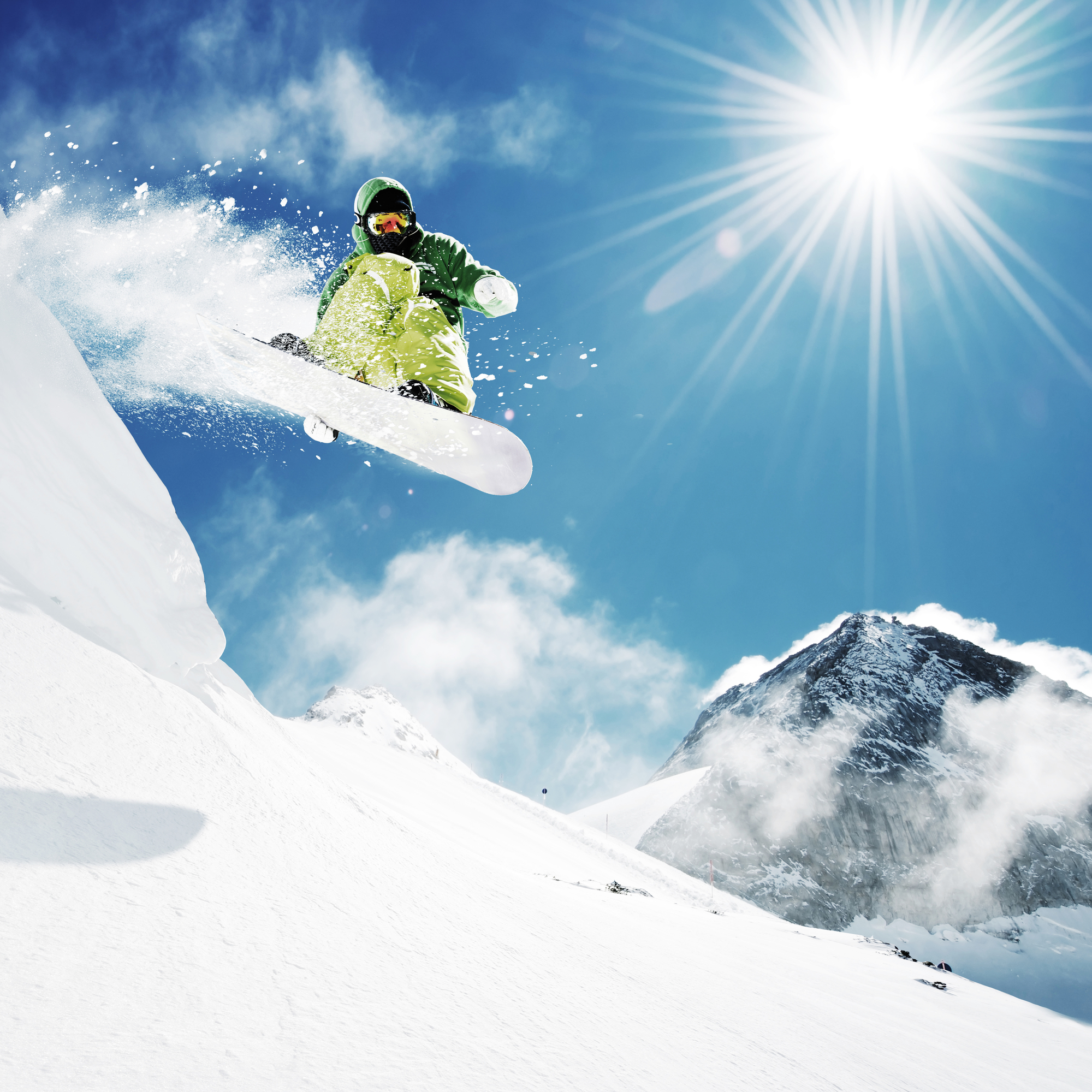 Snowboarder at jump inhigh mountains at sunny day.