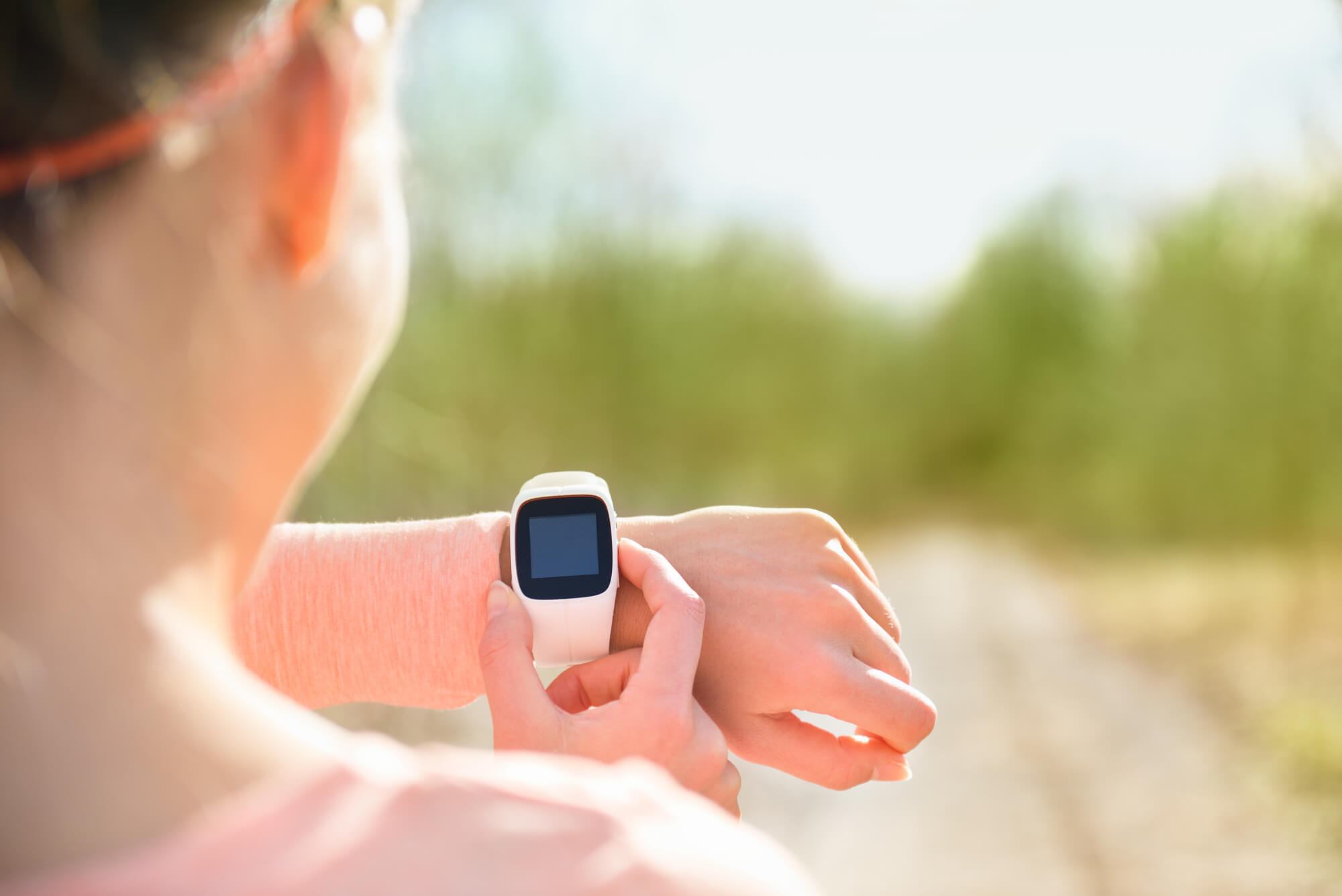 Female runner looks at wearable technology.