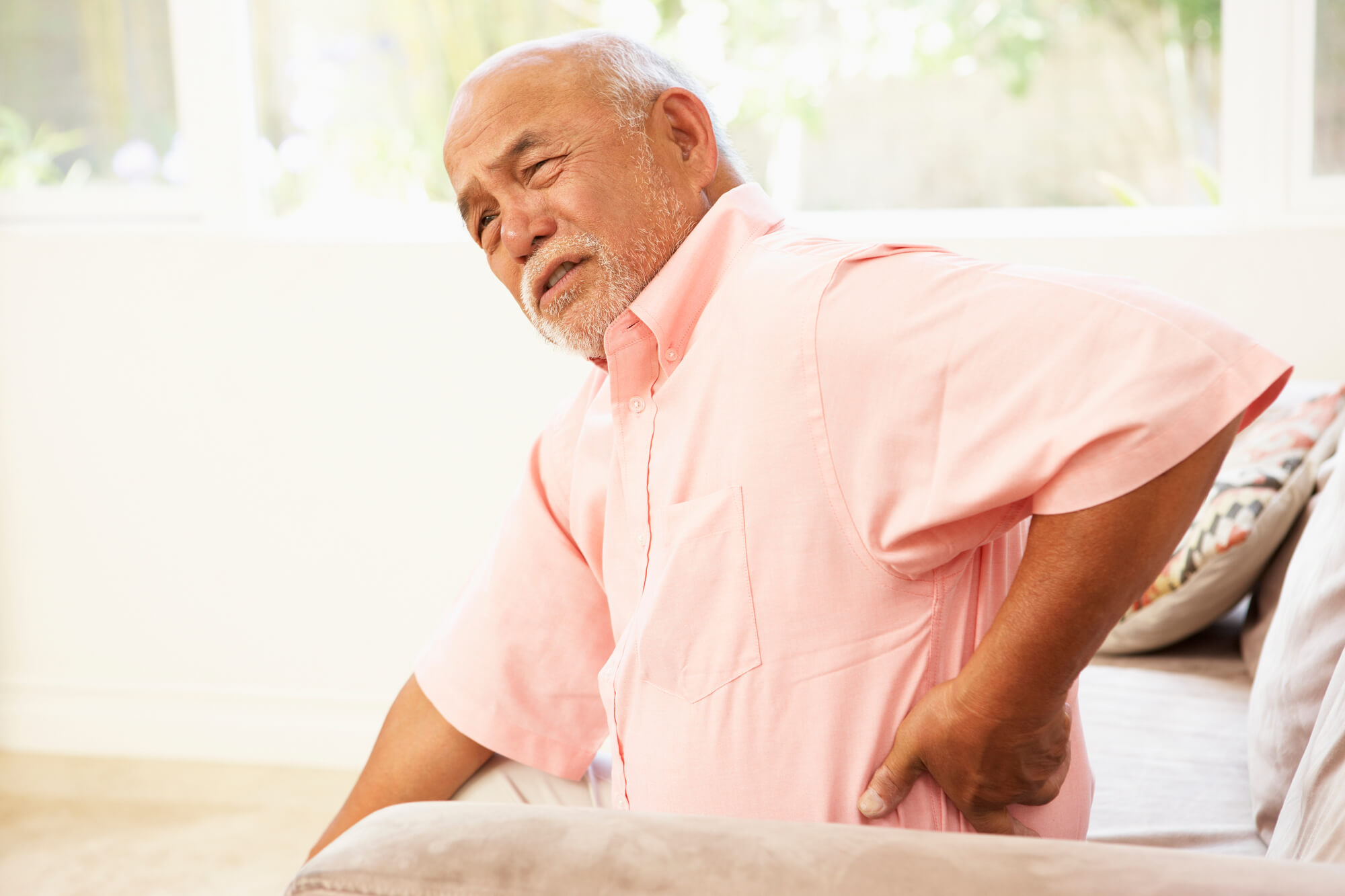 Senior man grabbing lower back in pain.