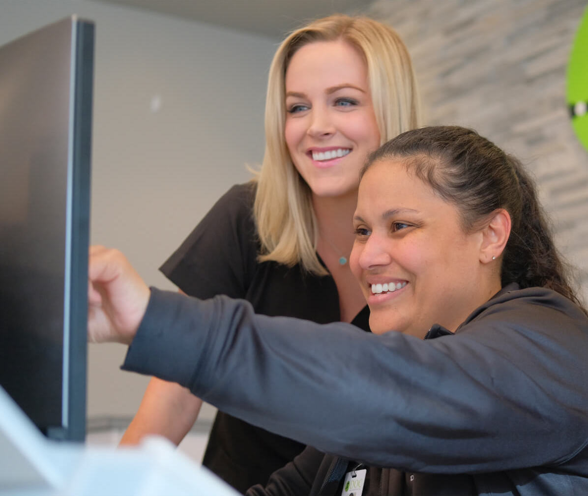 Two DOC employees smiling as they review notes on a computer.
