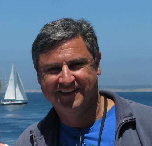 Headshot of Charlie posing in front of the ocean.