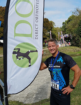 Dan stands next to a DOC flag banner on race day.