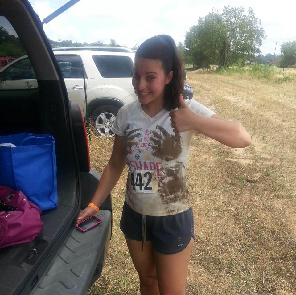 Myranda smiles and gives a thumbs up after participating in a mud run.