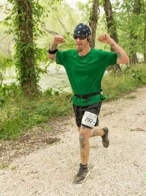 Action shot of Noah flexing for the camera while participating in a race on a trail outside.