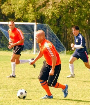 Action shot of Scott Mays dribbling a soccer ball during a game.