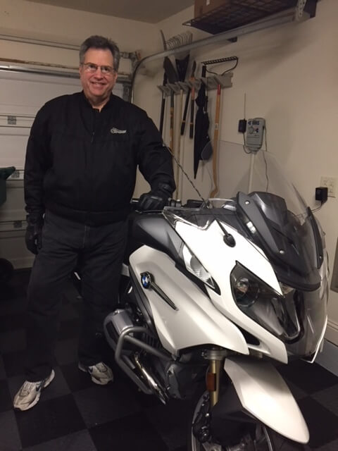 Tom Evan standing next to a motorcycle in a garage.