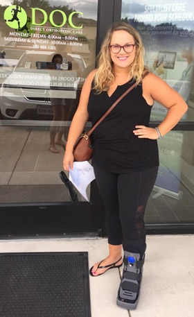 Annaliese standing outside a DOC clinic with a brace on her lower leg.