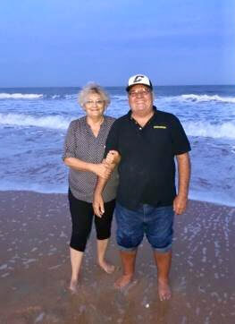 Susan and her partner standing on the beach.