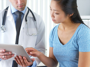 Doctor looking at tablet with female patient.