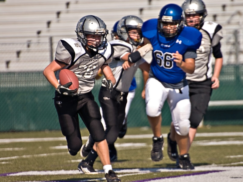 Young football players running during game.