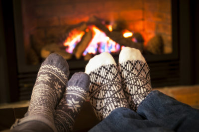 Feet in cozy winter socks warming by a fireplace.