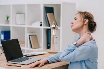 Woman Sitting at Desk Holding Painful Neck