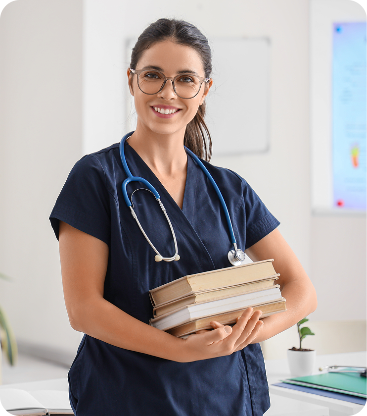 smiling female physician in scrubs holding stack of books